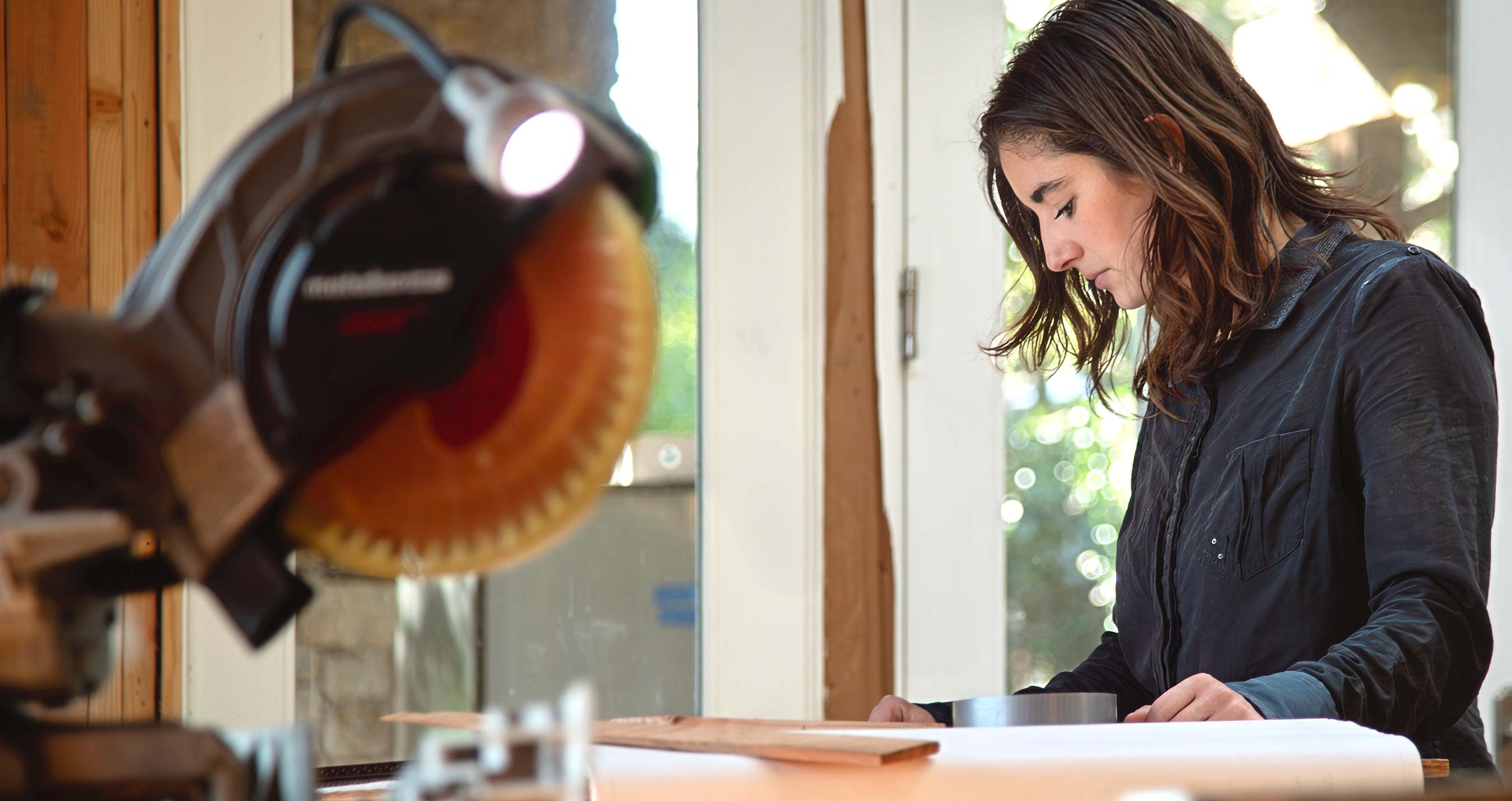 Alexandra Oliva Examines Plans on Job Site with Table Saw in Foreground