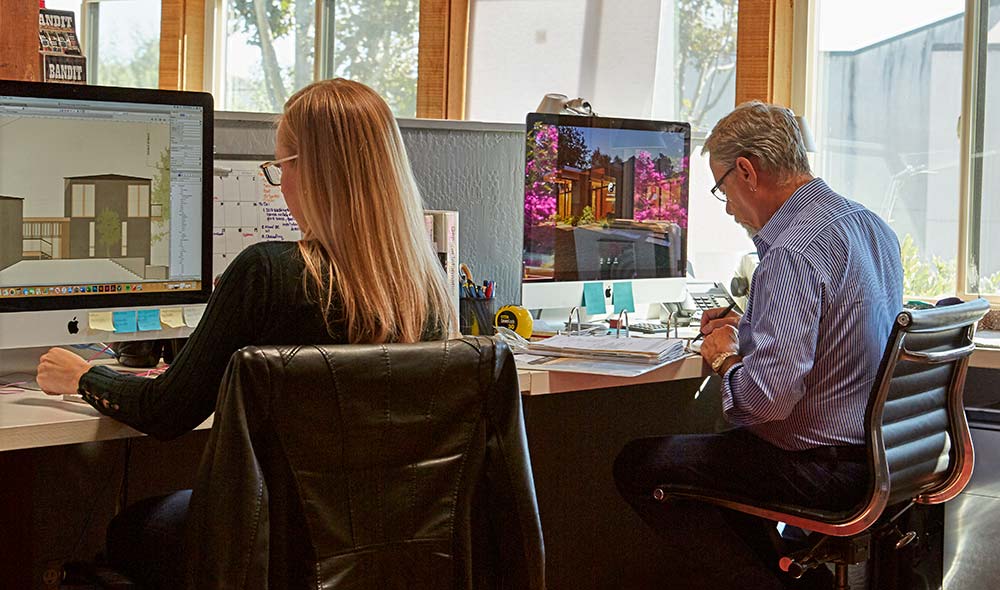 Two Workers at Desk with Computer Monitors